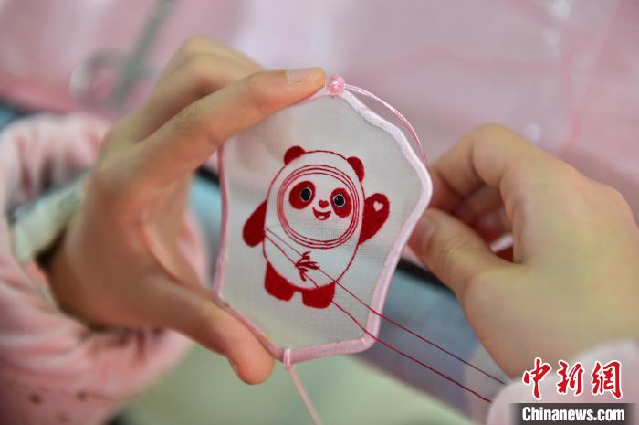 圖為一名小學(xué)生正在繡制2022年北京冬奧會(huì)吉祥物“冰墩墩”形象?！∮髟屏?攝