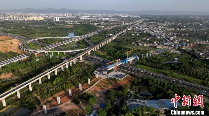 航拍正在建設的跨越成都繞城高速公路連續(xù)梁施工現(xiàn)場，旁邊依次為已運營的成渝高速鐵路和機場高速公路?！⒅铱?攝