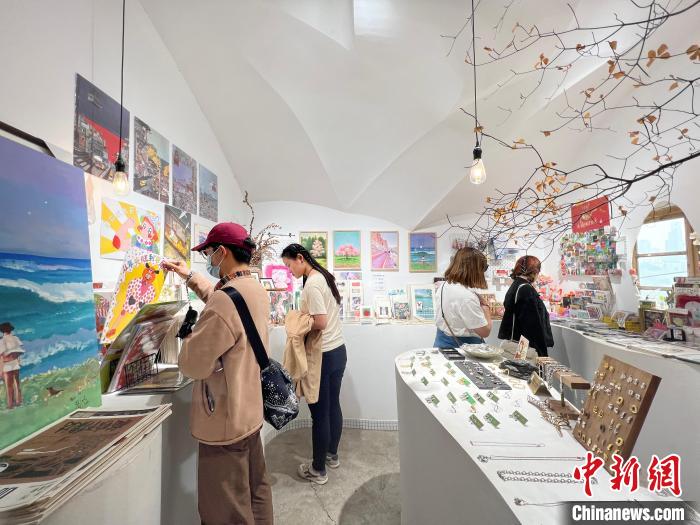 圖為藝術(shù)品商店內(nèi)，顧客挑選插畫作品?！＄婌?攝