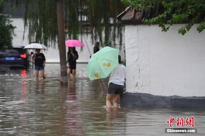 7月31日，市民行走在雨中的北京房山區(qū)瓦窯頭村。北京市氣象臺當(dāng)日10時發(fā)布分區(qū)域暴雨紅色預(yù)警信號。北京市水文總站發(fā)布洪水紅色預(yù)警，預(yù)計當(dāng)日12時至14時，房山區(qū)大石河流域?qū)⒊霈F(xiàn)紅色預(yù)警標準洪水。<a target='_blank' href='/'><p  align=