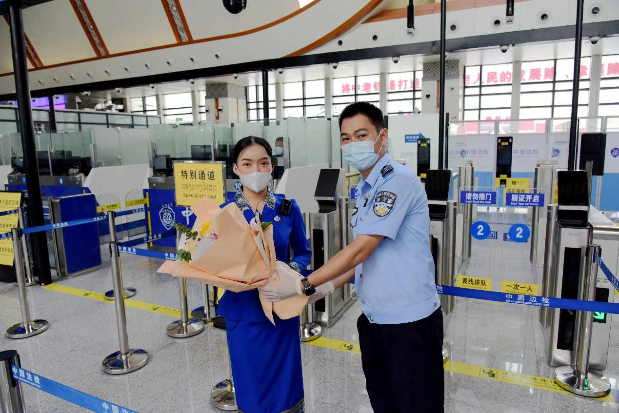 磨憨出入境邊防檢查站民警為中老鐵路第100萬名出入境旅客，D888次國際旅客列車?yán)蠐爰藙?wù)員森達(dá)拉·妮緹婭（Sengdala Nitiya），送上鮮花。黃遠(yuǎn)飛 攝