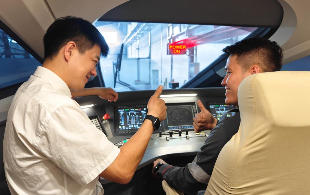 8月25日，在印度尼西亞萬隆的雅萬高鐵德卡魯爾動車所內(nèi)，中國師傅穆振（左）在向印尼火車司機(jī)塞蒂亞萬講解動車組出庫前的上電作業(yè)。