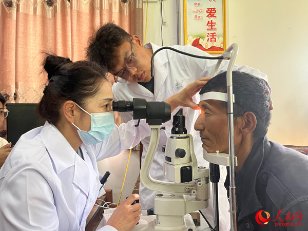 王紅英（左）和團(tuán)隊(duì)成員為達(dá)熱村村民檢查眼睛。人民網(wǎng)記者 杜燕飛攝