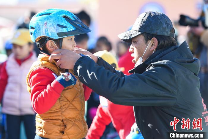 圖為拉薩市實(shí)驗(yàn)幼兒園孩子在教練的幫助下穿戴頭盔?！『闻罾?攝