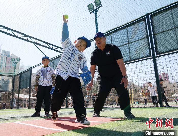 圖為來自臺灣的棒球教練劉興鴻(右)指導(dǎo)小棒球手?jǐn)S球技術(shù)?！●R銘言 攝