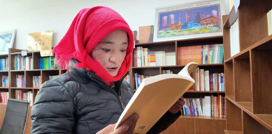 一名婦女正在認(rèn)真閱讀書籍。申扎縣融媒體中心供圖