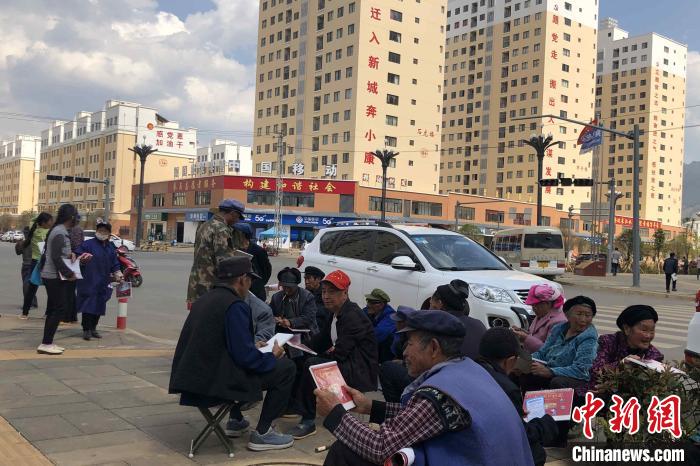 圖為會(huì)澤縣城易地扶貧搬遷安置點(diǎn)內(nèi)，老人們聚在廣場上聊天，身后是他們的新家。　繆超 攝