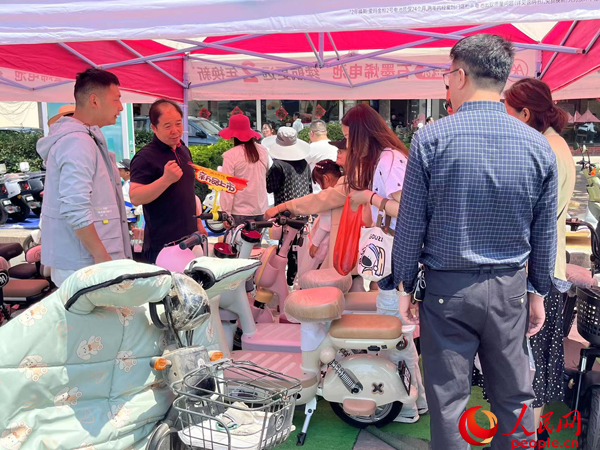 某電動(dòng)自行車品牌工作人員向消費(fèi)者介紹以舊換新相關(guān)情況。人民網(wǎng)記者 杜燕飛攝