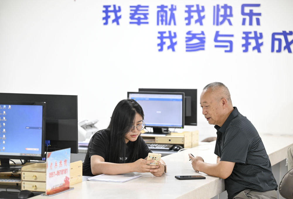 2024年6月20日，在寧夏銀川市金鳳區(qū)長(zhǎng)城花園社區(qū)黨群服務(wù)中心，工作人員幫助居民辦理業(yè)務(wù)。圖片來(lái)源 新華社