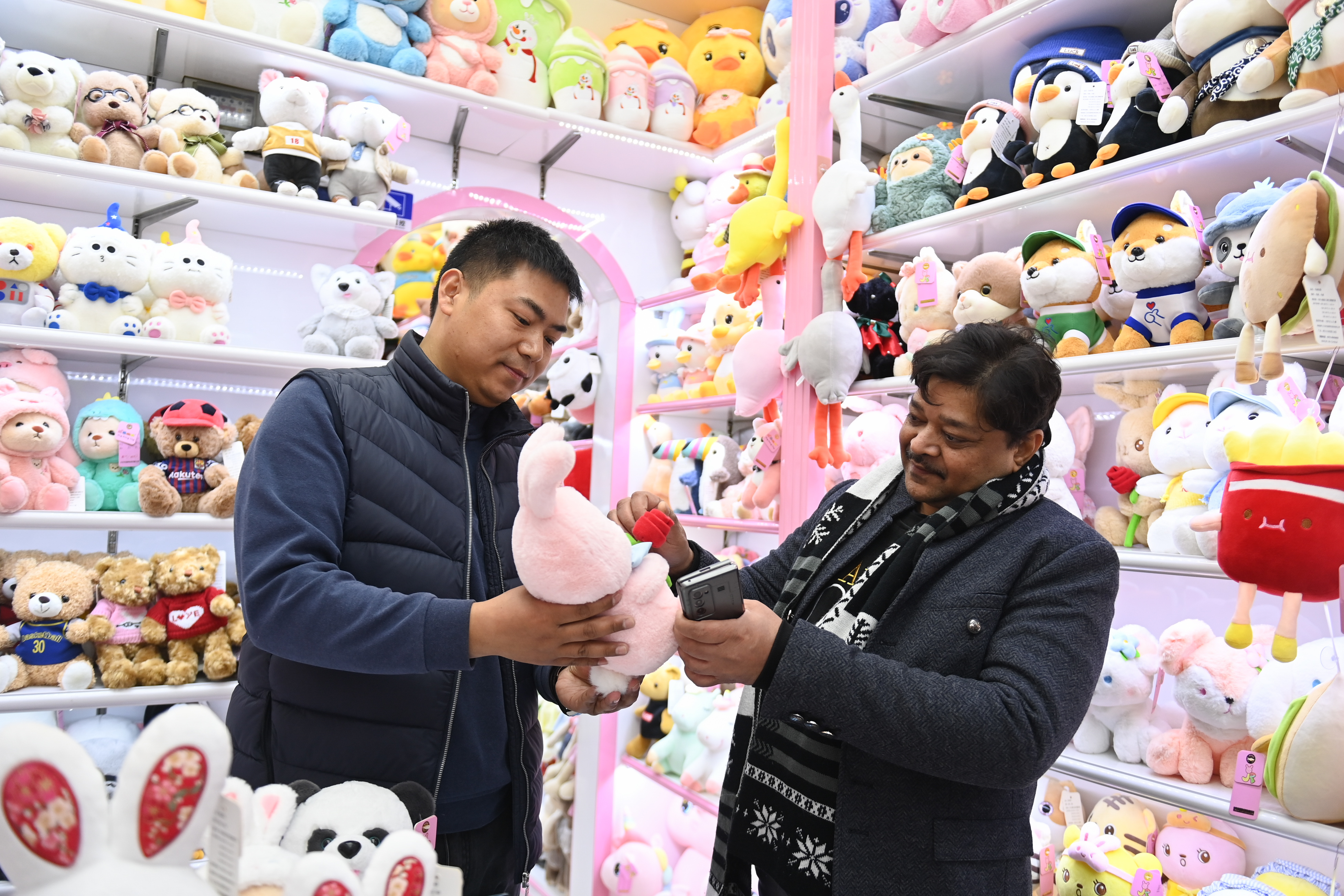 2023年2月2日，來自印度的客商（右）在義烏國際商貿(mào)城的一家玩具店鋪內(nèi)選購。