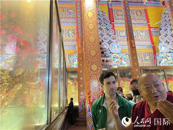 7月25日，省級非物質(zhì)文化遺產(chǎn)項目塔爾寺酥油花的代表性傳承人朋措堅參（右）在塔爾寺酥油花館講解酥油花的制作過程。人民網(wǎng) 謝瑩攝