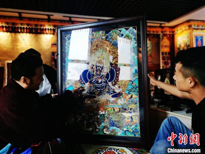 圖為久美尖措(左)與徒弟們展示唐卡作品?！?zhí)砀?攝