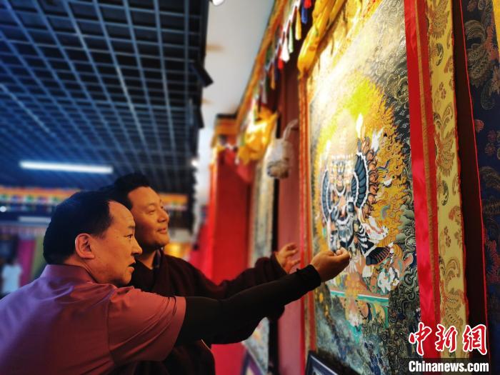 圖為久美尖措展示唐卡作品?！?zhí)砀?攝