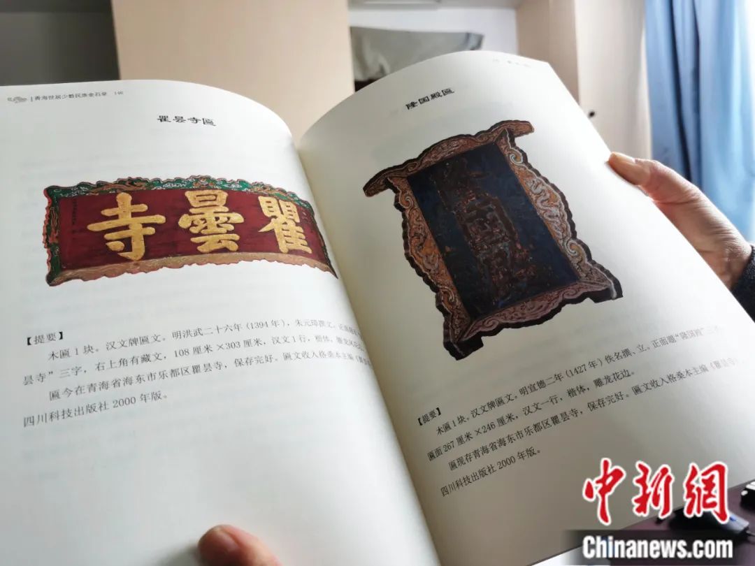 古籍保護(hù)人員展示介紹明代朱元璋撰寫(xiě)的青海瞿曇寺匾(左)的出版書(shū)籍。張?zhí)砀?攝