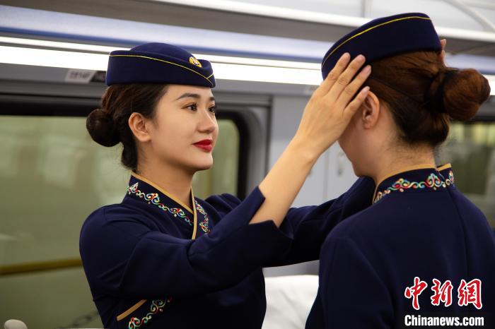 圖為青藏鐵路西格段“復(fù)興號(hào)”動(dòng)車組乘務(wù)員互相整理新制服?！±罾?攝