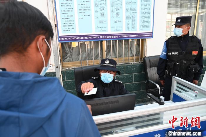 圖為移民管理警察登記完身份信息后將證件歸還給行人?！≮w朗 攝
