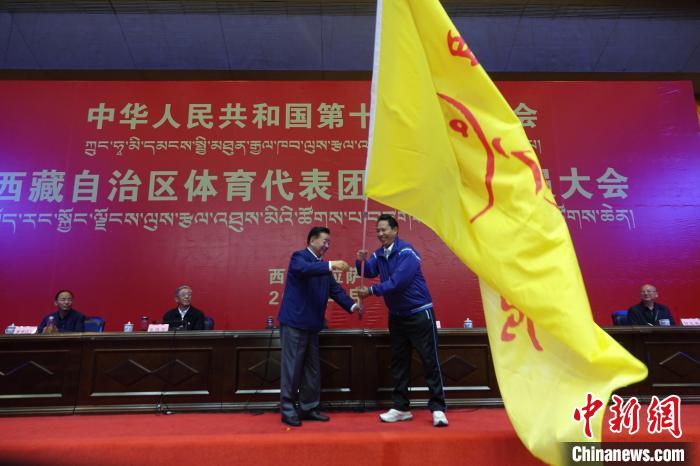 西藏自治區(qū)副主席甲熱·洛桑丹增授代表團團旗，西藏自治區(qū)體育局局長尼瑪次仁接旗?！∪轿木?攝