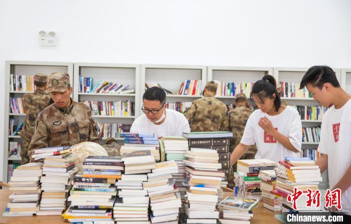 圖為志愿者們和邊防戰(zhàn)士整理圖書?！詵| 攝