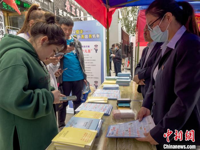 圖為工作人員正在向路過市民介紹國家反詐中心軟件的功能?！≈x牧 攝