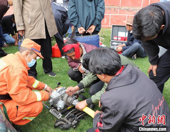 圖為森林消防員為護(hù)林員講解滅火裝備的使用方法?！〔际猩窒乐ш?duì) 供圖