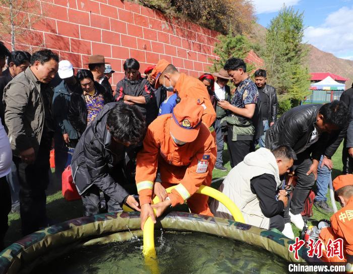 圖為森林消防員為護(hù)林員講解滅火裝備的使用方法?！〔际猩窒乐ш?duì) 供圖
