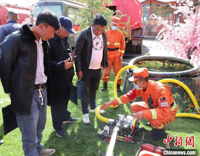 圖為森林消防員為護(hù)林員講解滅火裝備的使用方法?！〔际猩窒乐ш?duì) 供圖
