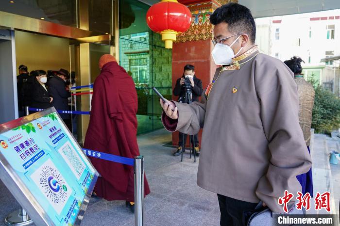 圖為政協(xié)委員掃場所碼進入會場?！〗w波 攝