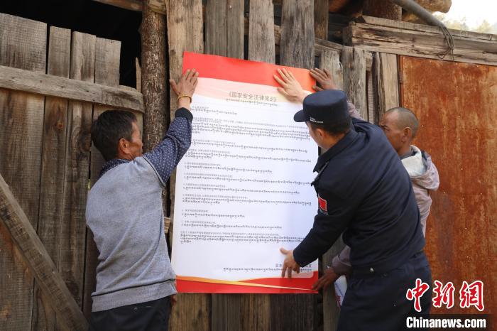 圖為亞?wèn)|邊檢站民警與駐地邊民群眾共同張貼國(guó)家安全知識(shí)教育海報(bào)?！?wèn)|邊檢站 供圖