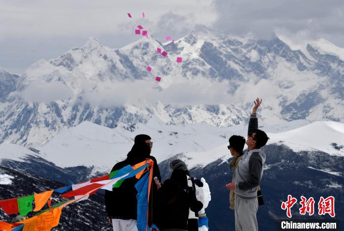 圖為5月14日，游客在西藏林芝色季拉山觀景臺拋灑“隆達(dá)”(風(fēng)馬旗，藏族民眾的一種祈福方式)?！±盍?攝